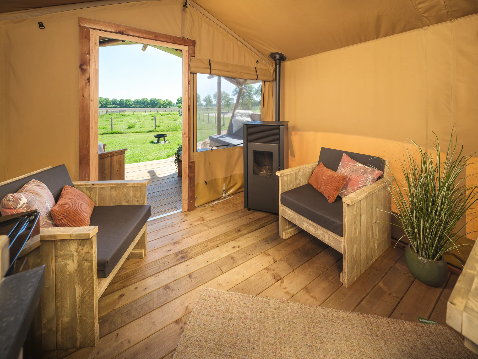 Wood Lodge Cozy: sala con sofá, sillón y estufa, con la puerta abierta a la terraza